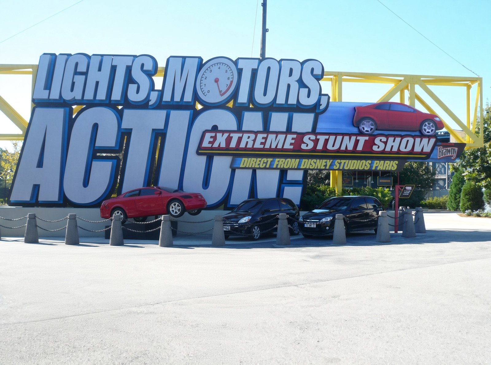 Placa da entrada do Lights, Motors, Action! com a inscrição direct from Disney Studios Paris, patrocínio Brawny e carros expostos