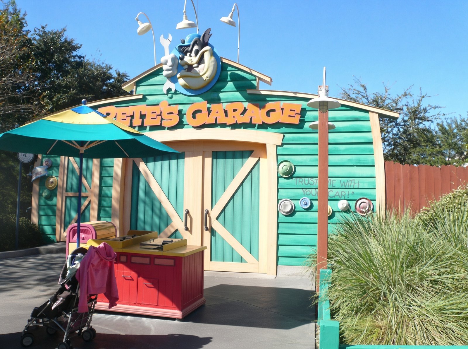 Fachada verde e amarela da Pete's Garage na Mickey's Toontown Fair com o personagem Pete como mecânico acima da entrada