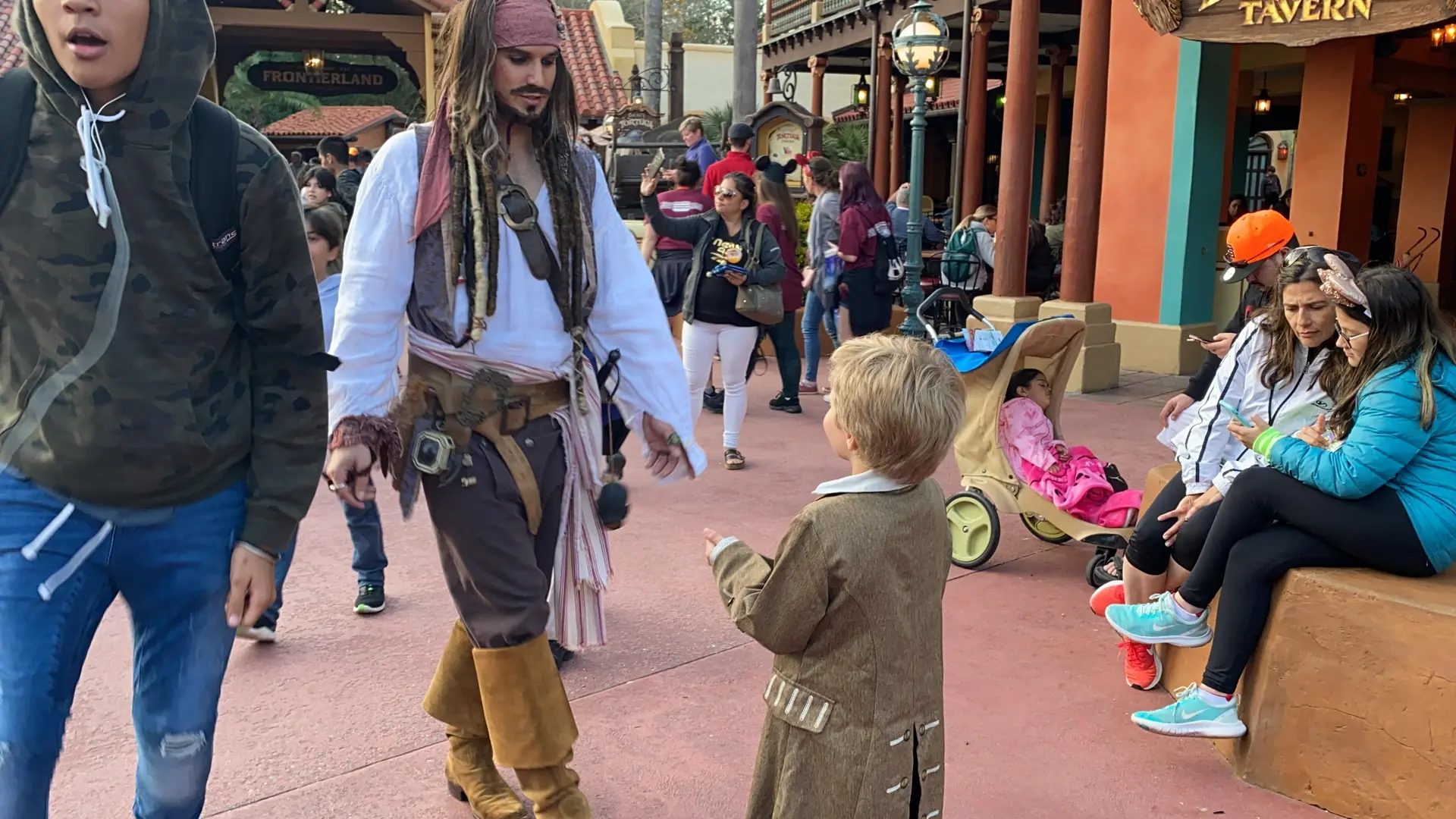 Criança fantasiada, de costas, interagindo com Jack Sparrow no Magic Kingdom