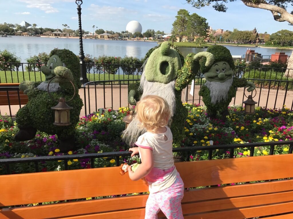 Topiarias de três dos Sete Anões e flores à beira da lagoa no Epcot