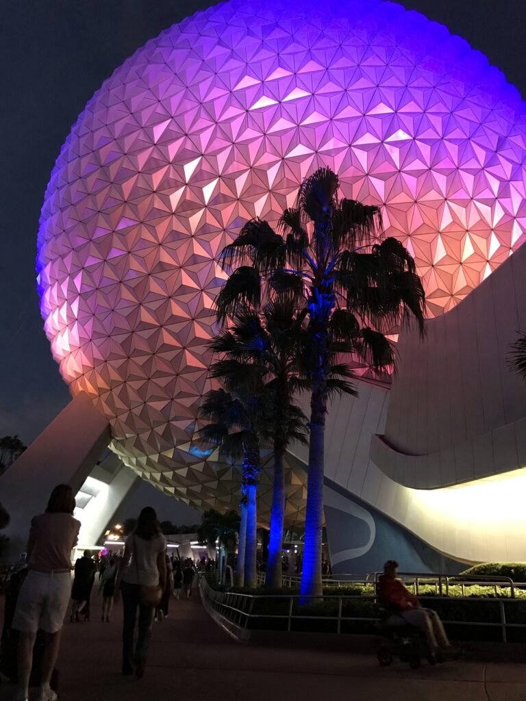 Spaceship Earth iluminada em tons de rosa e roxo à noite
